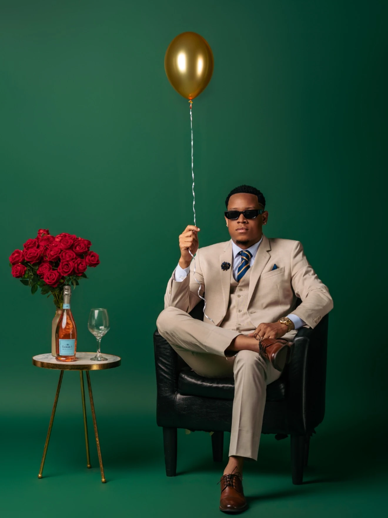 Jemar Lyon seated in a beige suit against a green studio backdrop