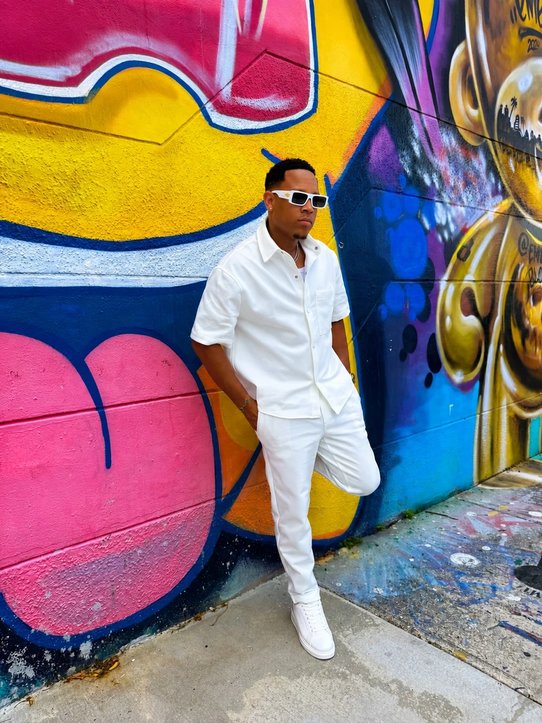 Jemar Lyon dressed in white beside a colourful Miami mural